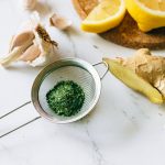 A flat lay of garlic, ginger, and lemon on a marble surface for natural remedies.